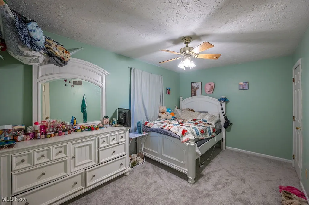 Bedroom featuring light colored carpet, a textured ceiling, and a ceiling fan