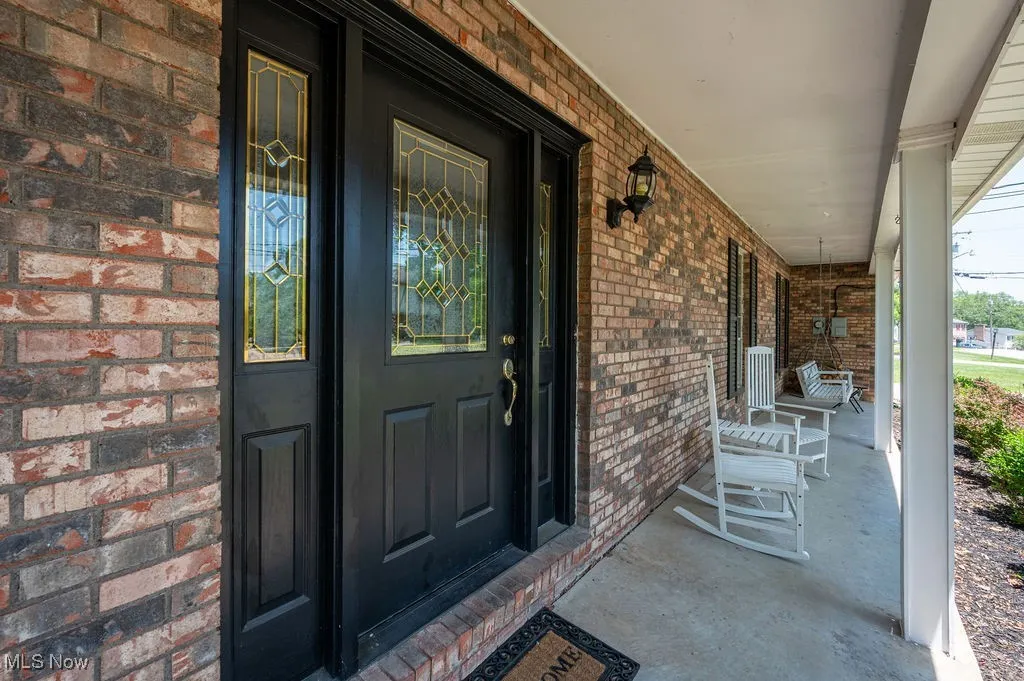 Entrance to property featuring covered porch and brick siding