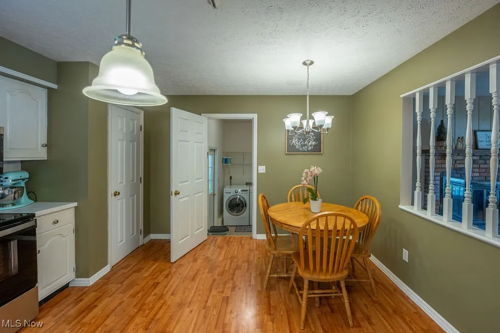 Dining room with washer / clothes dryer, light wood-style flooring, a chandelier, and a textured ceiling