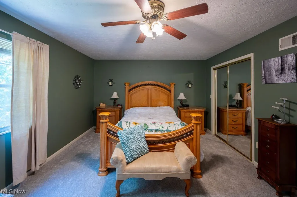 Carpeted bedroom with a closet, a ceiling fan, and a textured ceiling