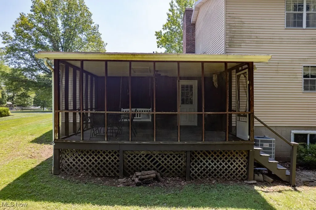 Rear view of property featuring a sunroom, a yard, and a chimney