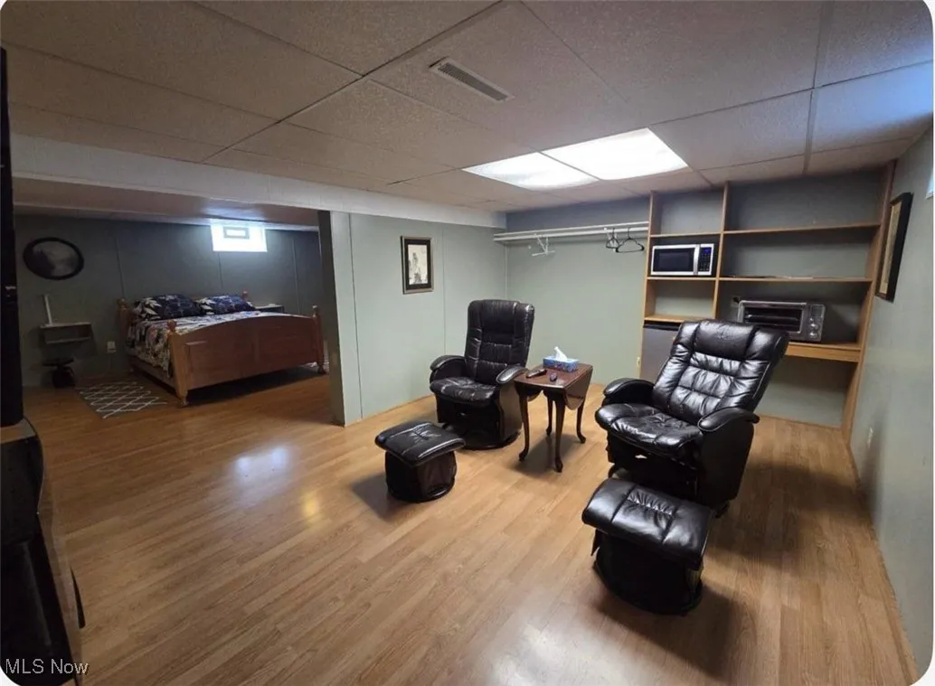 Living area featuring wood finished floors and a drop ceiling
