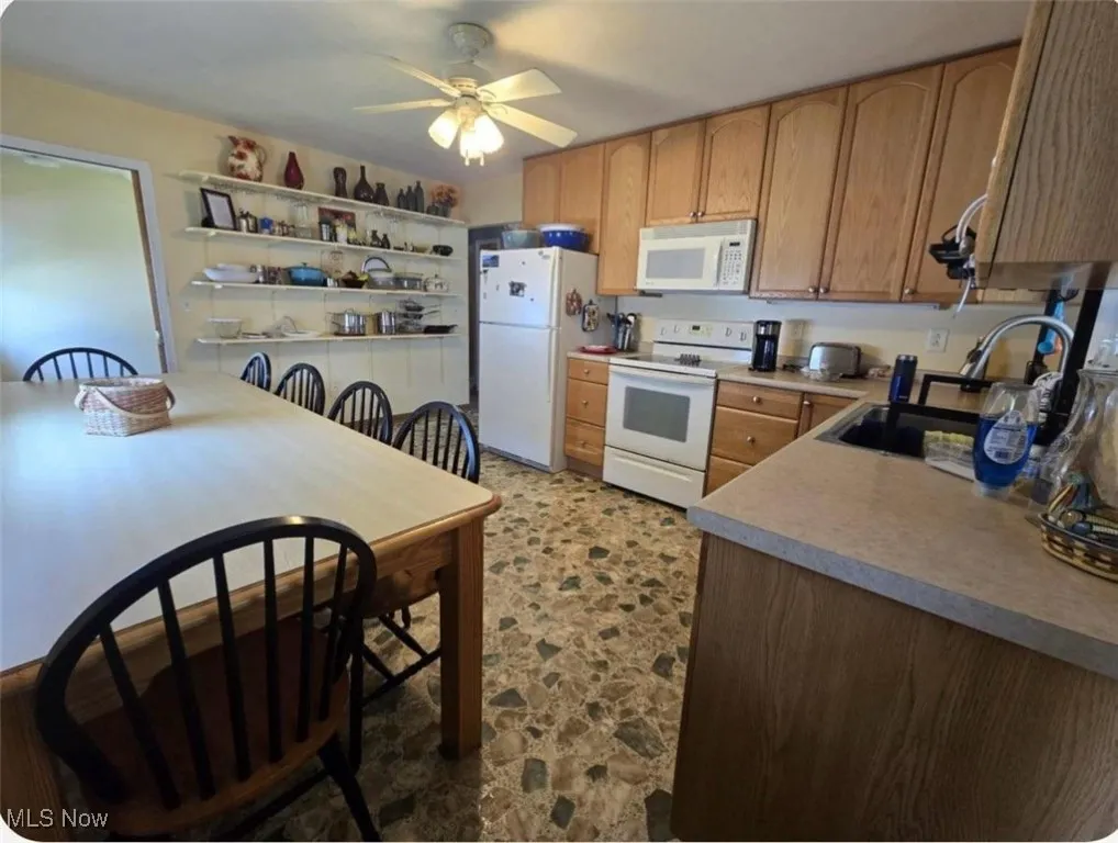 Kitchen featuring white appliances, a ceiling fan, open shelves, and light countertops