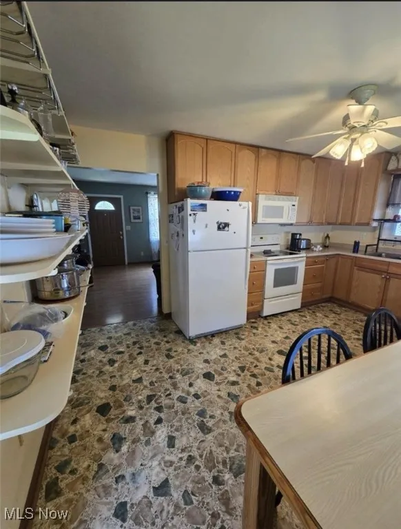 Kitchen featuring white appliances, dark stone finish floors, a ceiling fan, and light countertops