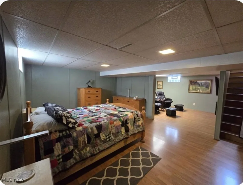 Bedroom with a paneled ceiling and wood finished floors