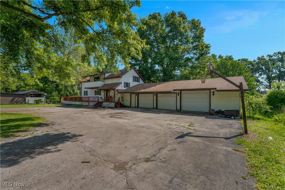 View of front of home with an attached garage, driveway, and a deck