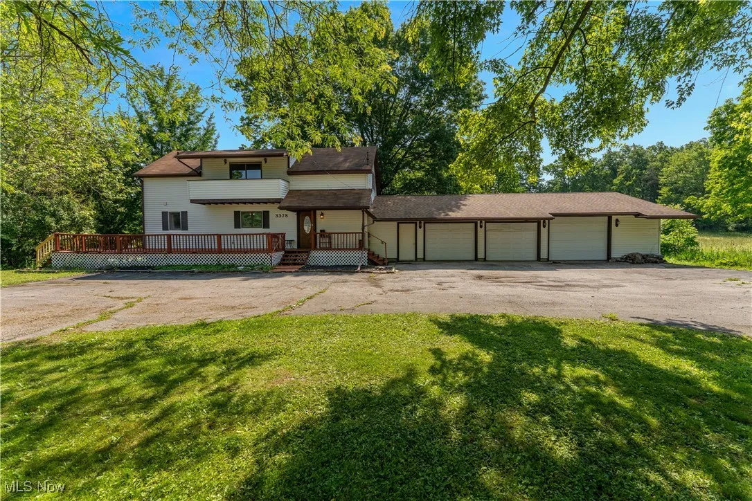 View of front of house with driveway, a front yard, a garage, and a wooden deck