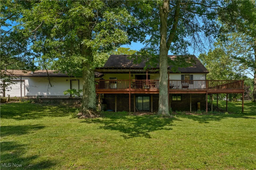 Back of property featuring a wooden deck and a lawn