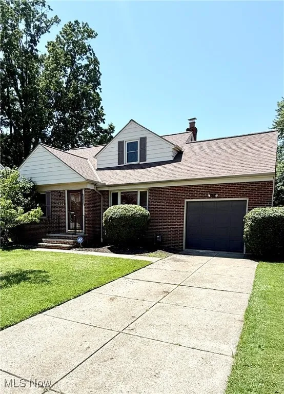 Traditional-style home featuring a garage, brick siding, concrete driveway, a front lawn, and roof with shingles