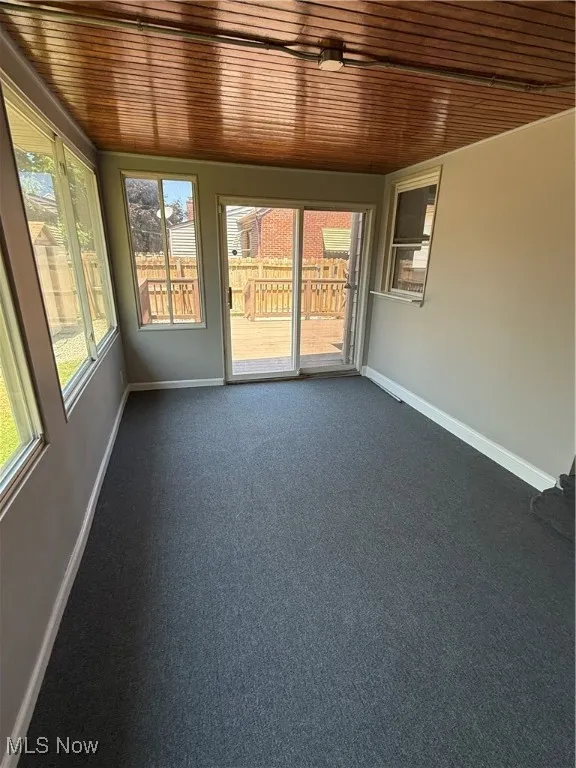 Unfurnished sunroom with wooden ceiling and carpet floors