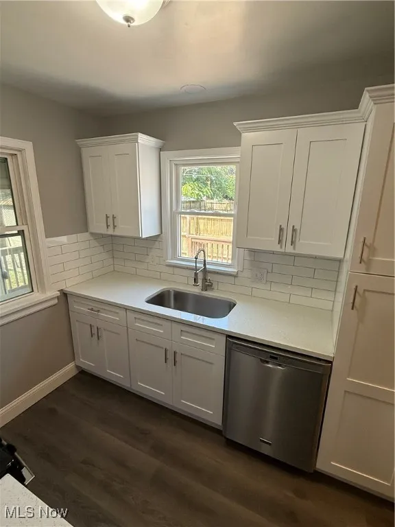 Kitchen featuring dishwashing machine, white cabinetry, light countertops, and tasteful backsplash