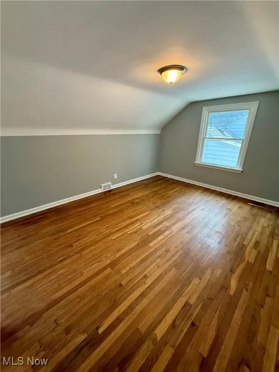 Bonus room featuring dark wood finished floors and lofted ceiling