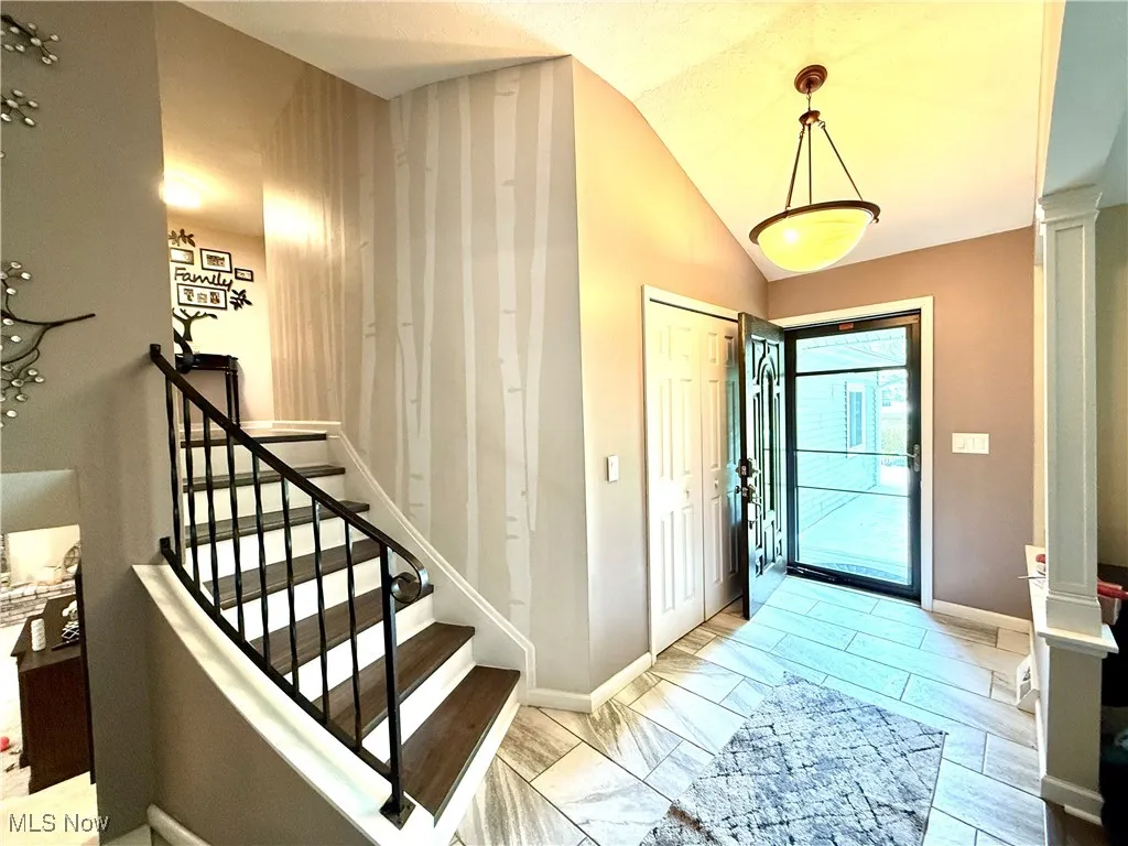 Foyer entrance with ornate columns, vaulted ceiling, and stairway