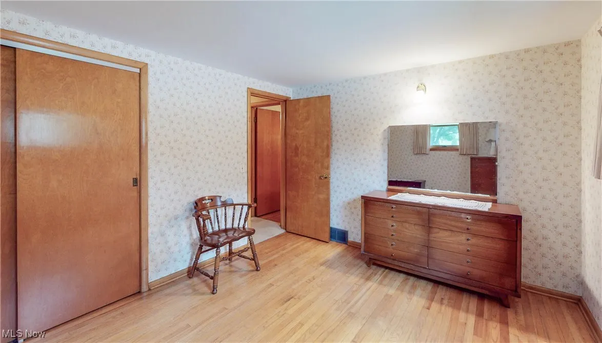 Bedroom featuring wood finished floors and wallpapered walls
