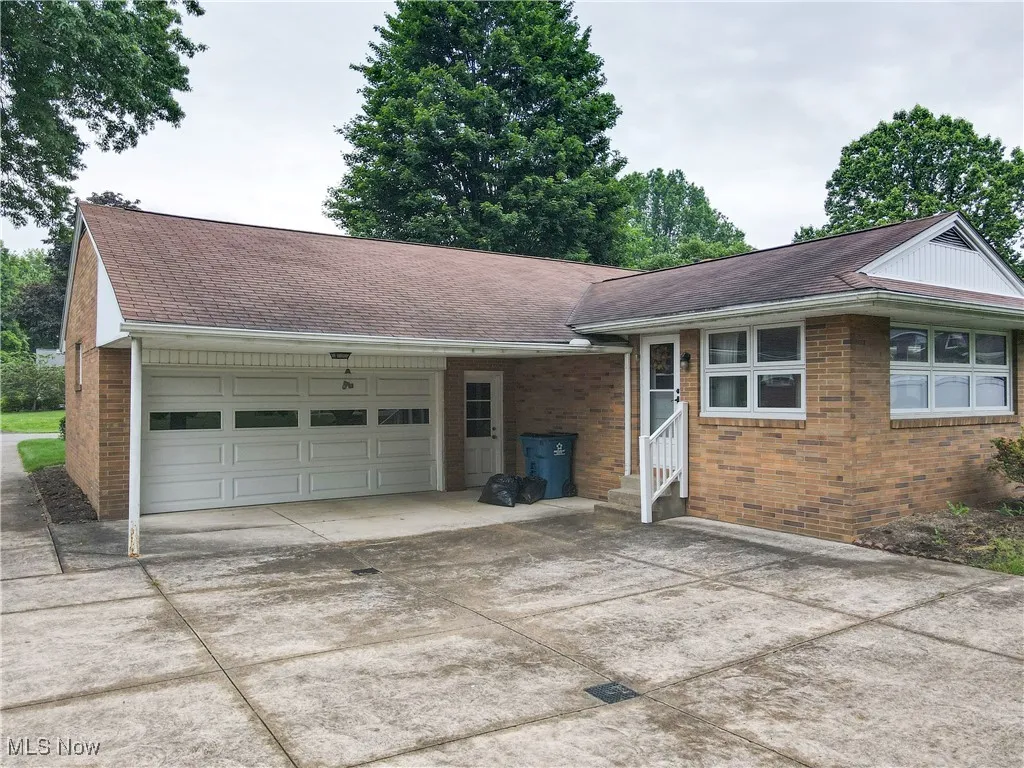 View of front of home featuring entry steps, concrete driveway, a garage, brick siding, and roof with shingles