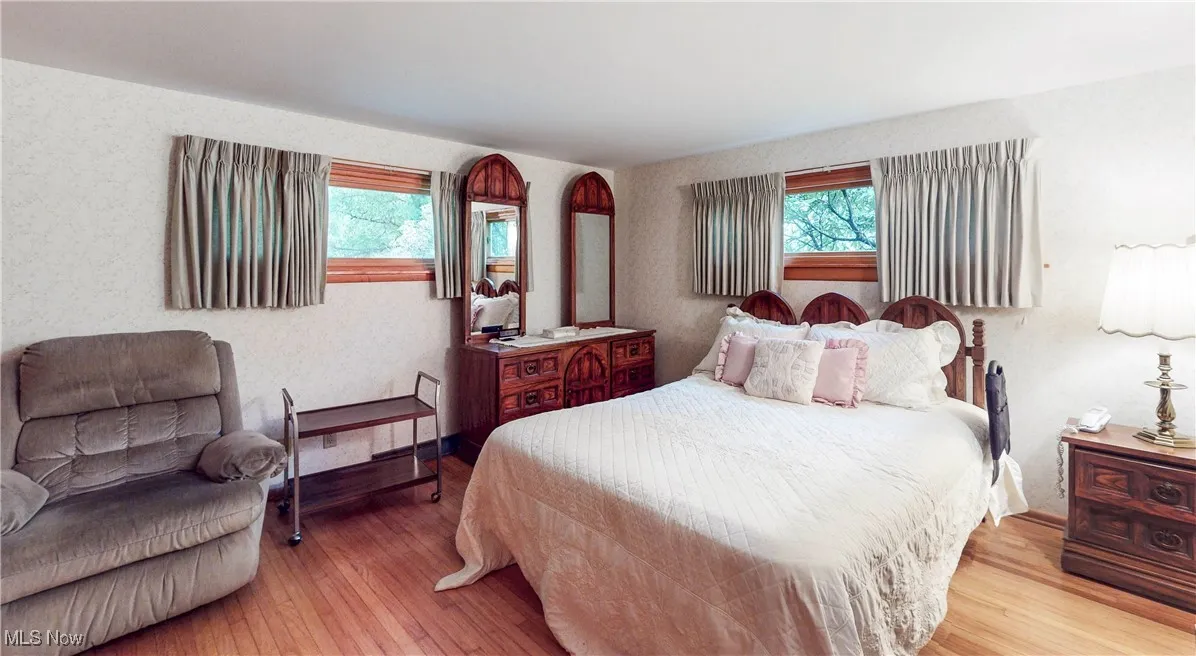 Bedroom with hardwood / wood-style flooring and multiple windows
