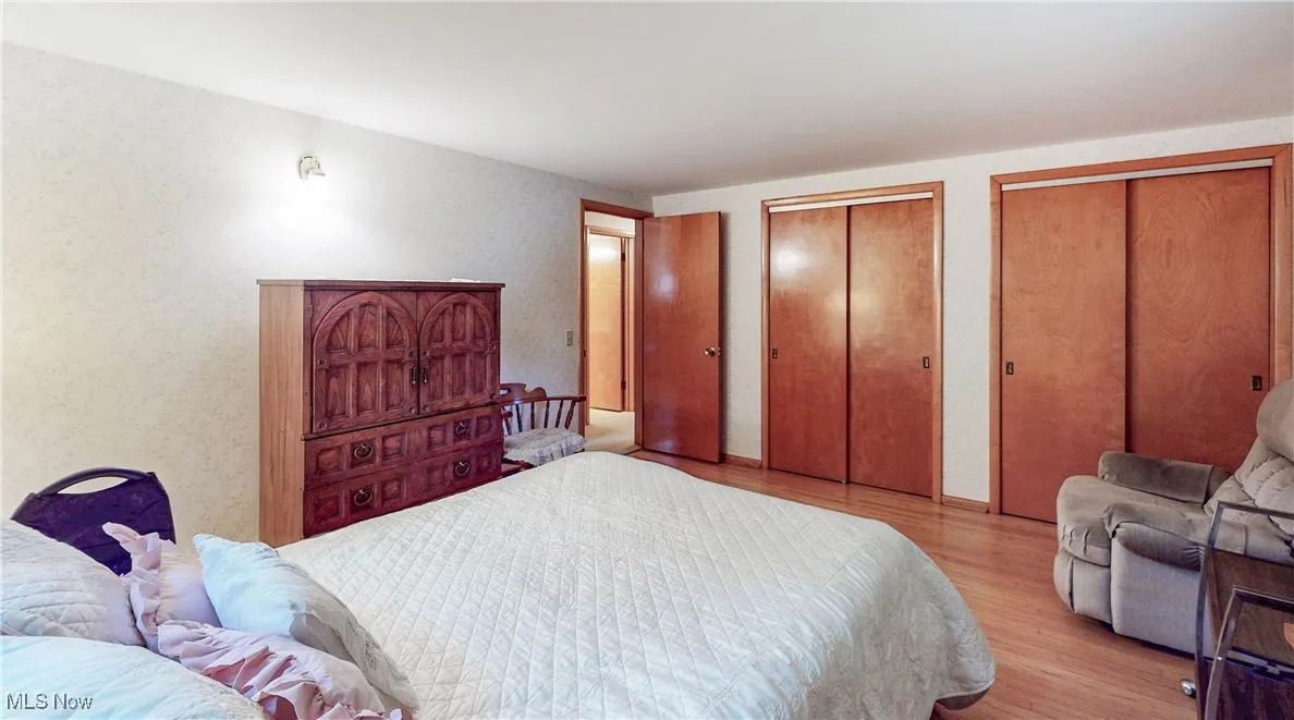 Bedroom with multiple closets and light wood-style floors