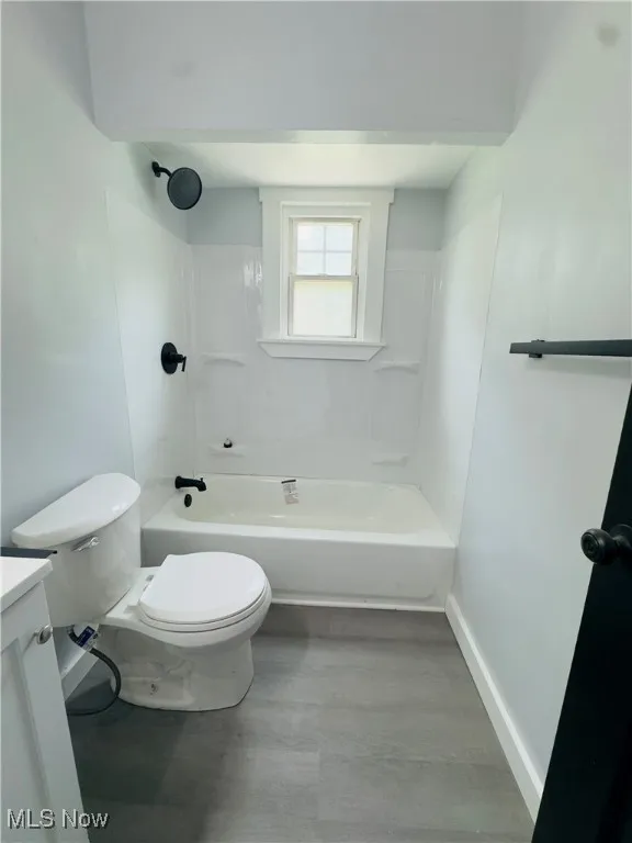 Bathroom featuring wood finished floors, vanity, and shower / washtub combination