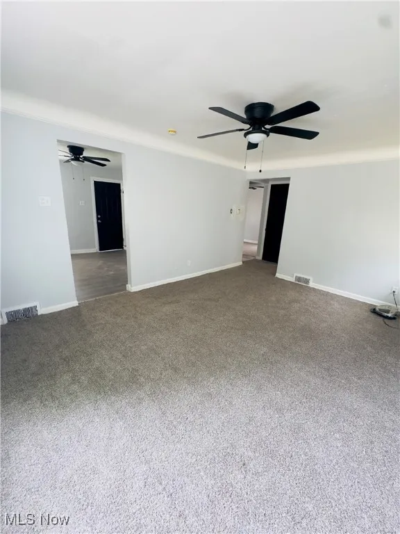 Empty room featuring ceiling fan and carpet floors
