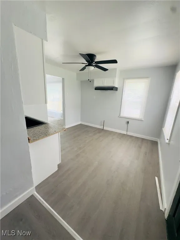 Unfurnished living room featuring wood finished floors, ceiling fan, and a wall mounted air conditioner