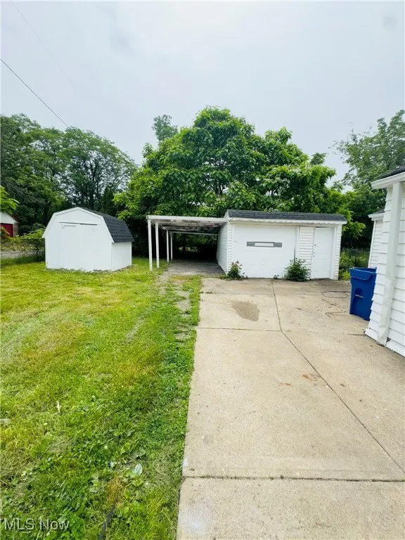 View of green lawn with a shed and concrete driveway