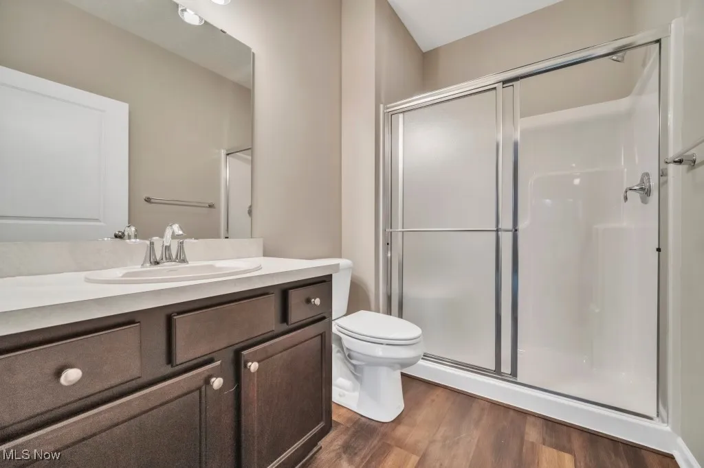 Bathroom featuring a stall shower, vanity, and wood finished floors