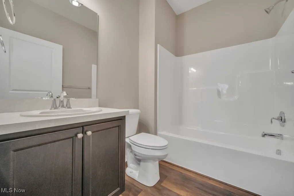 Full bath featuring wood finished floors, vanity, and  shower combination