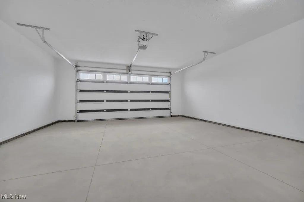 Garage featuring a garage door opener and baseboards