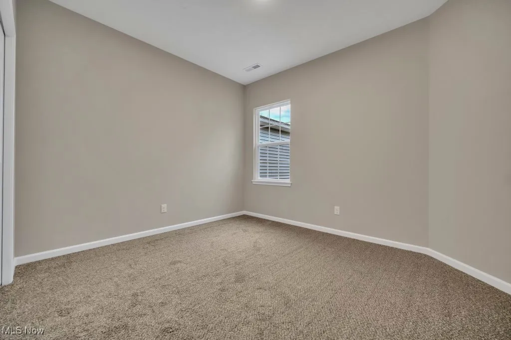 Carpeted spare room with baseboards and lofted ceiling