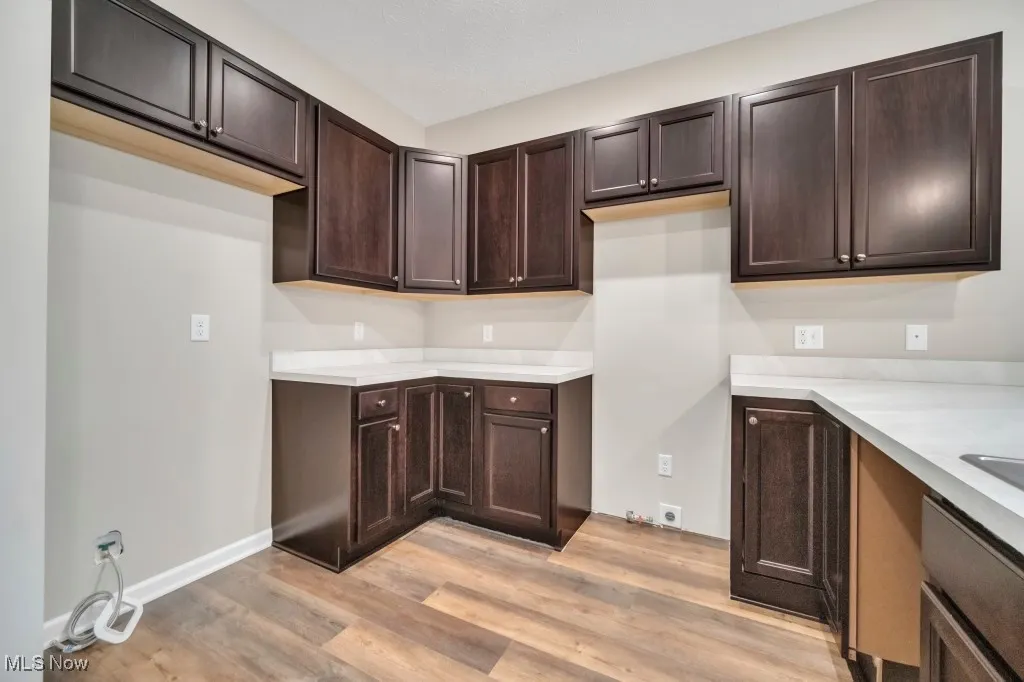 Kitchen with light wood-style flooring, dark brown cabinets, and light countertops