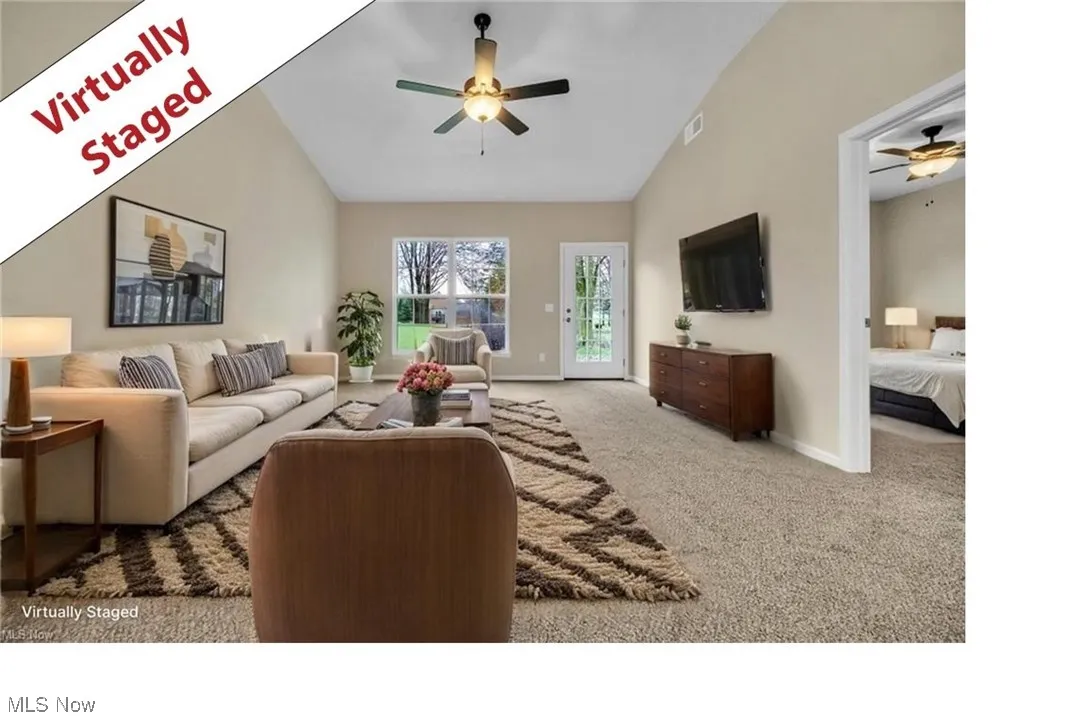 Carpeted living area with a ceiling fan and lofted ceiling