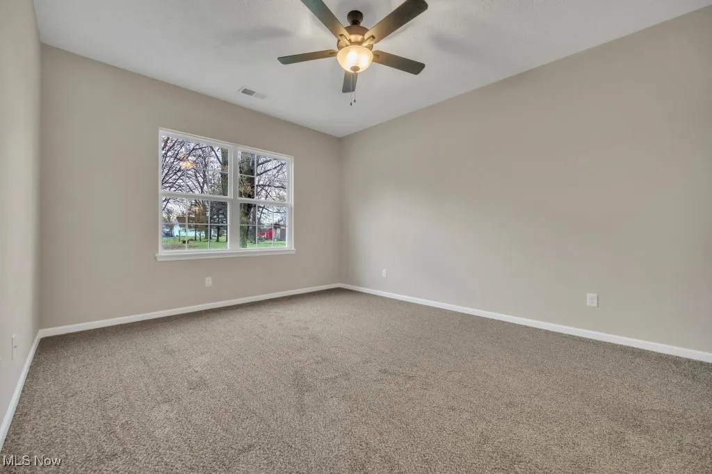 Carpeted spare room with baseboards and ceiling fan