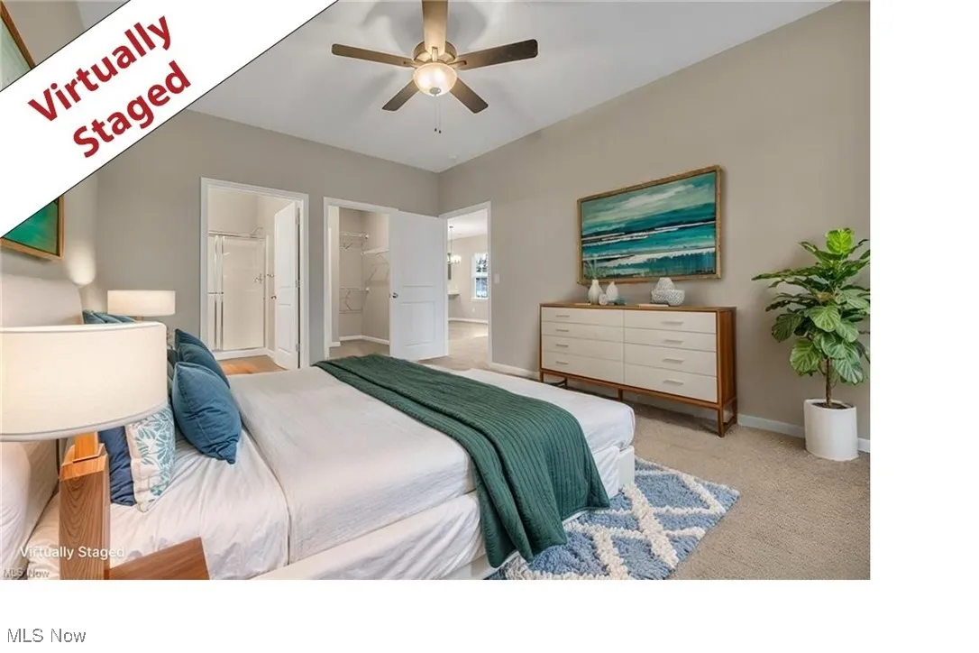 Bedroom featuring carpet floors, a ceiling fan, connected bathroom, and a walk in closet