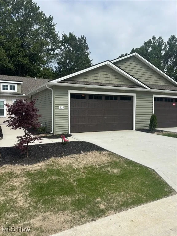 View of front of property with concrete driveway, an attached garage, and a front yard
