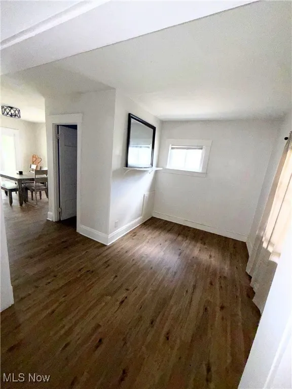Spare room with dark wood-style flooring and baseboards