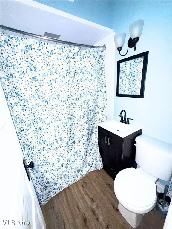 Full bath with vanity, dark wood-style floors, and a stall shower