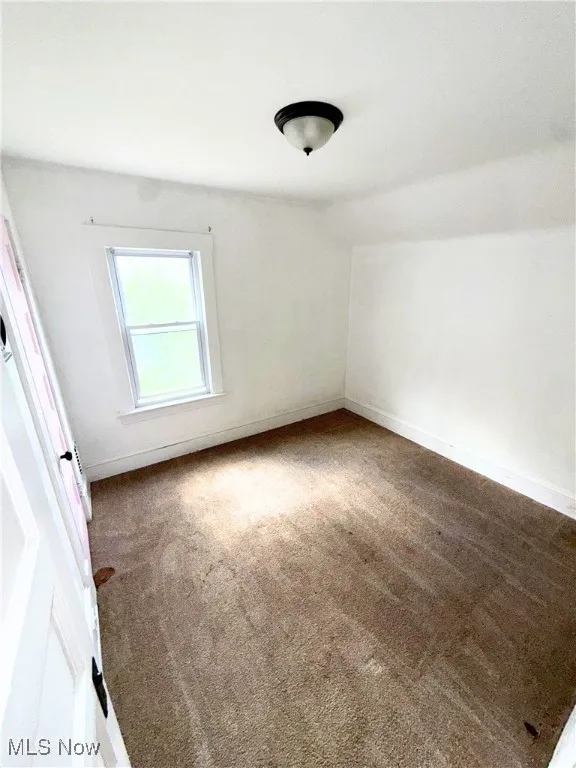Carpeted spare room featuring baseboards