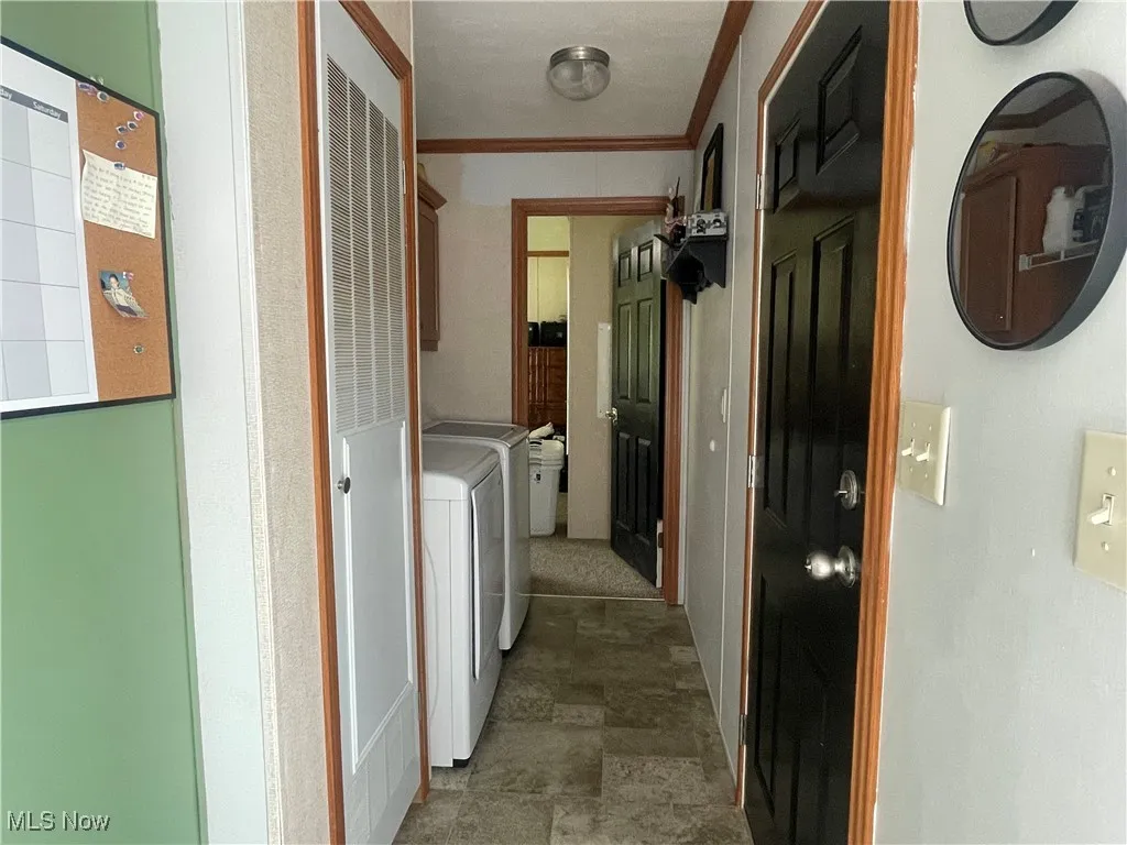 Washroom featuring cabinet space, washing machine and clothes dryer, stone finish flooring, ornamental molding, and a heating unit