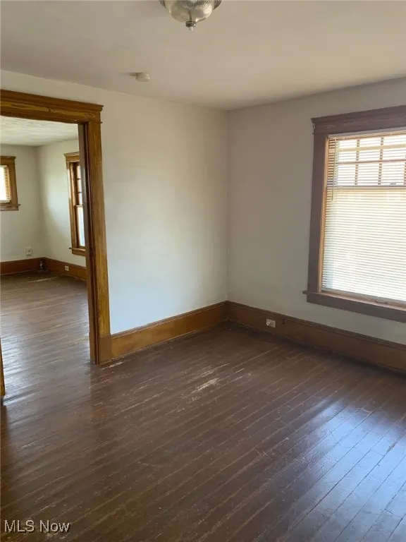Unfurnished room with dark wood-type flooring and a smoke detector