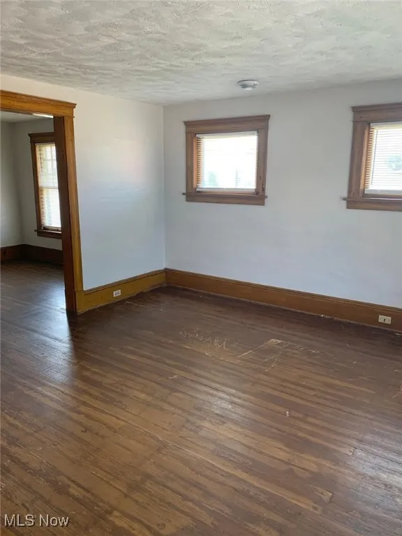 Empty room featuring dark wood finished floors and a textured ceiling