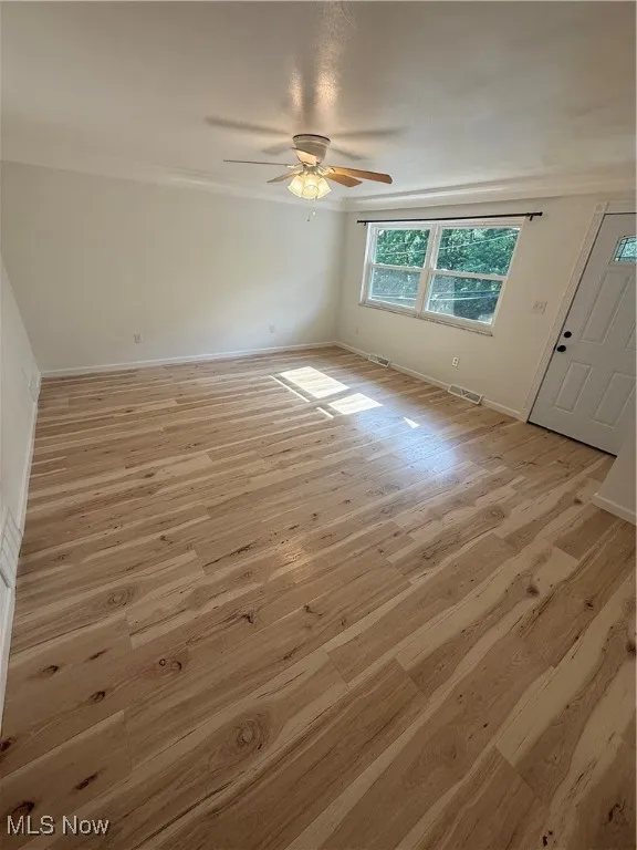 Spare room with light wood-style flooring, a ceiling fan, and ornamental molding