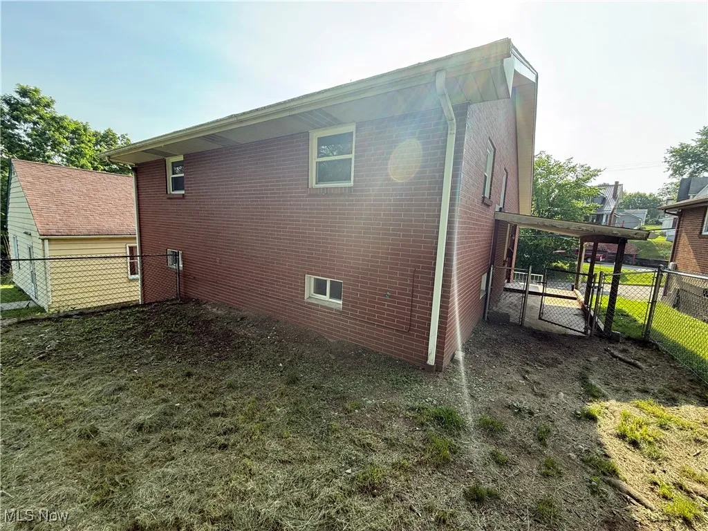 View of side of property featuring a gate and brick siding