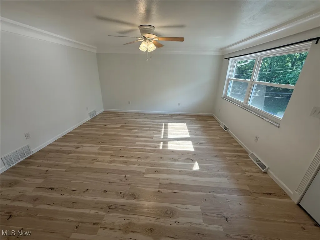 Spare room featuring ceiling fan, light wood-type flooring, and crown molding