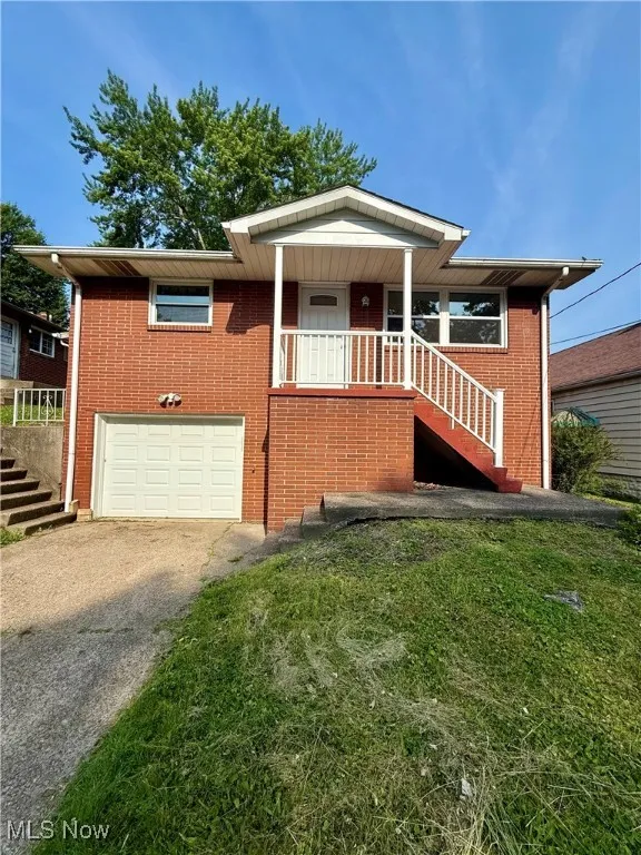 View of front of property with stairs, asphalt driveway, brick siding, and a garage