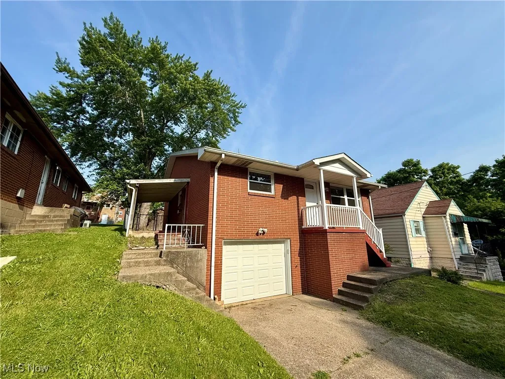 View of front of home with brick siding, concrete driveway, a garage, a front yard, and covered porch