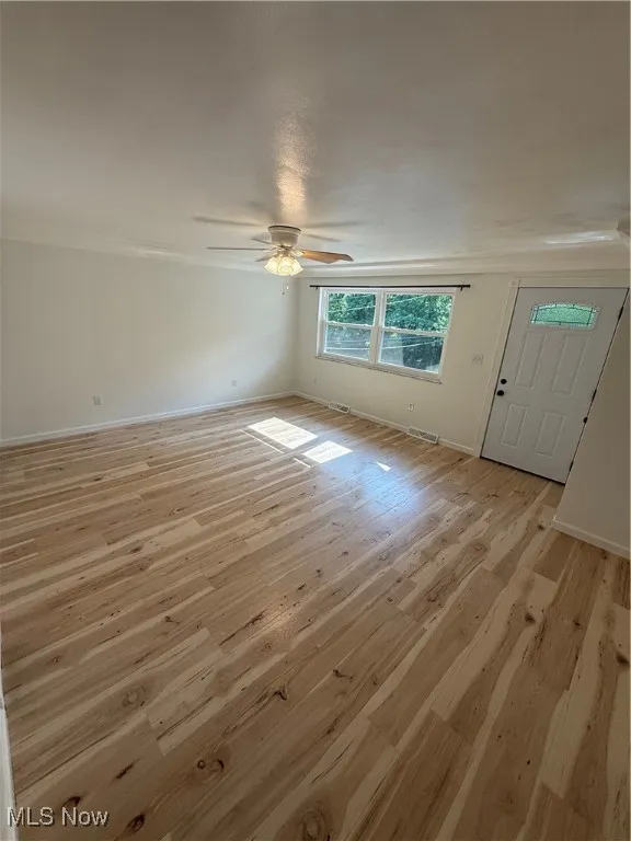 Unfurnished living room featuring light wood-type flooring and ceiling fan