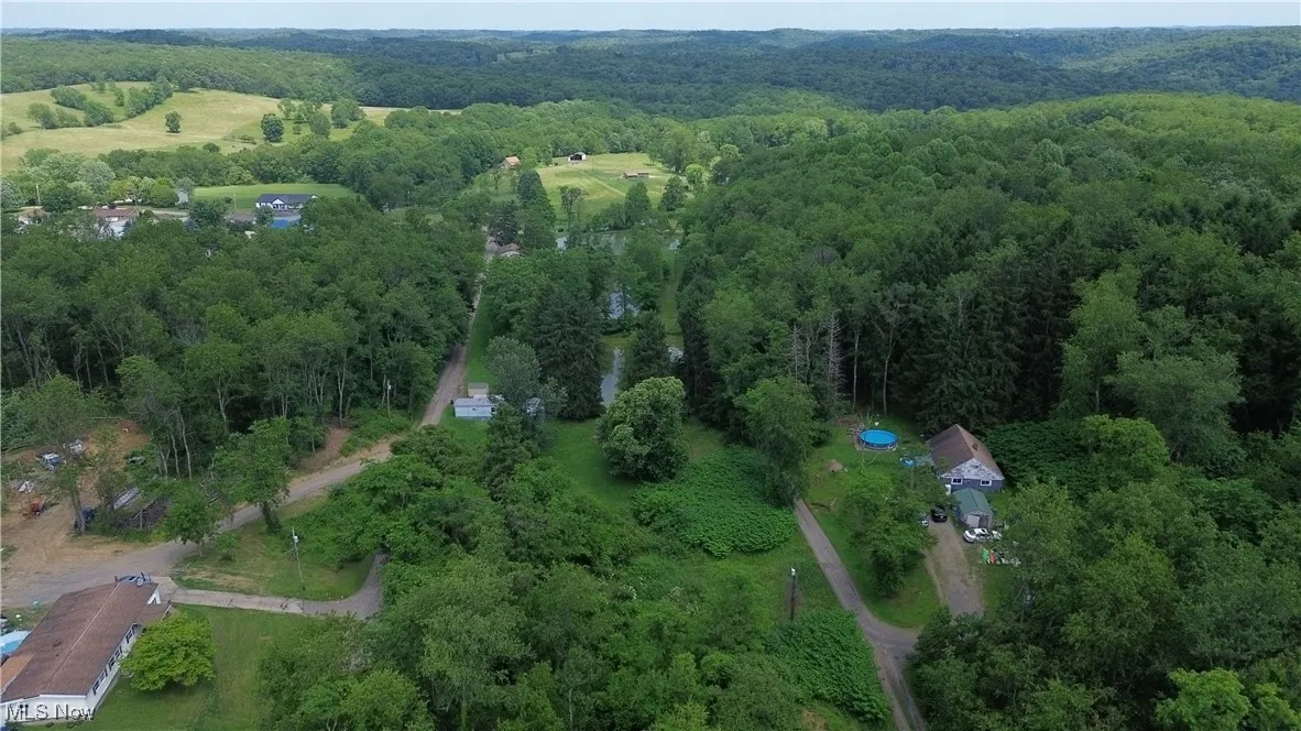 Aerial view of property and surrounding area with a forest