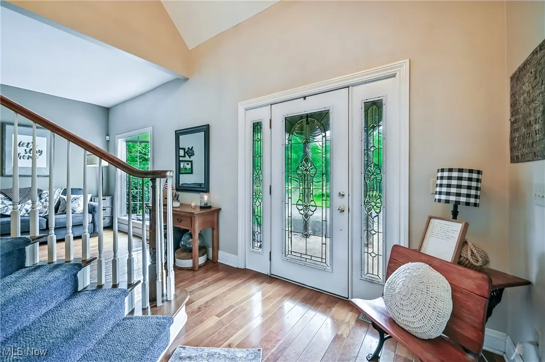 Entryway with stairs, leaded glass front door and side panels, wood floors and high vaulted ceiling