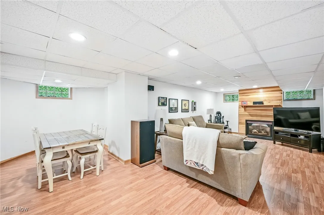 Living area featuring wood finished floors, recessed lighting, a glass covered fireplace, and a paneled ceiling