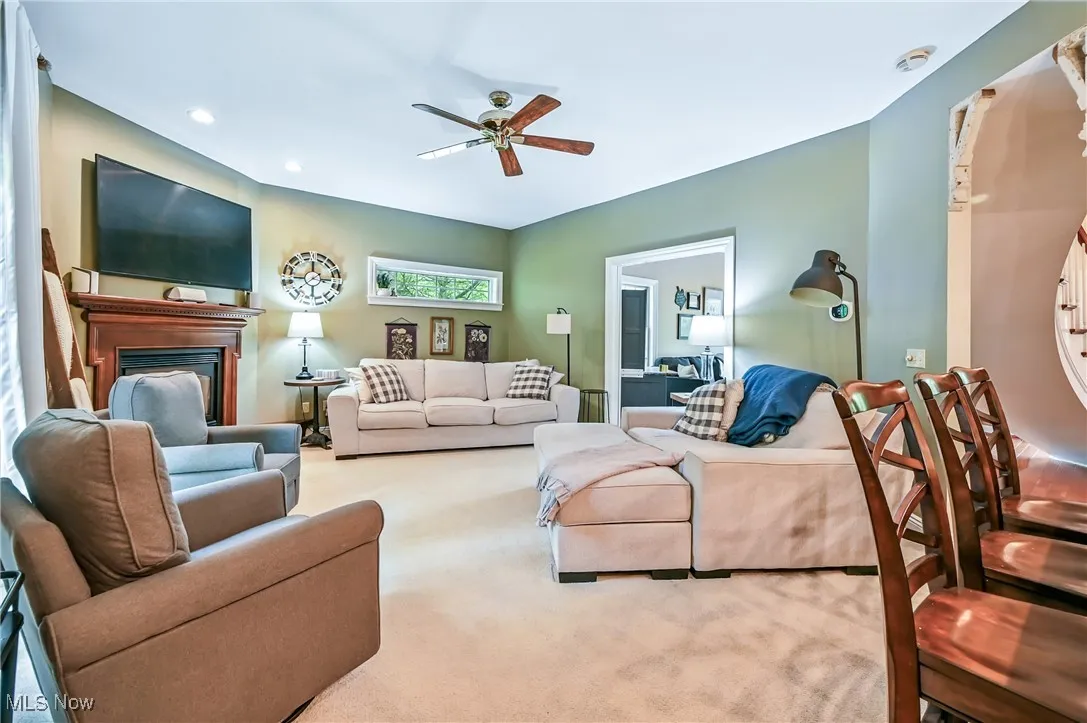 Living room with ceiling fan, carpet flooring, a fireplace, and recessed lighting